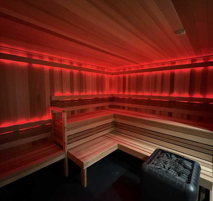Red-lit wooden sauna interior with heater and benches