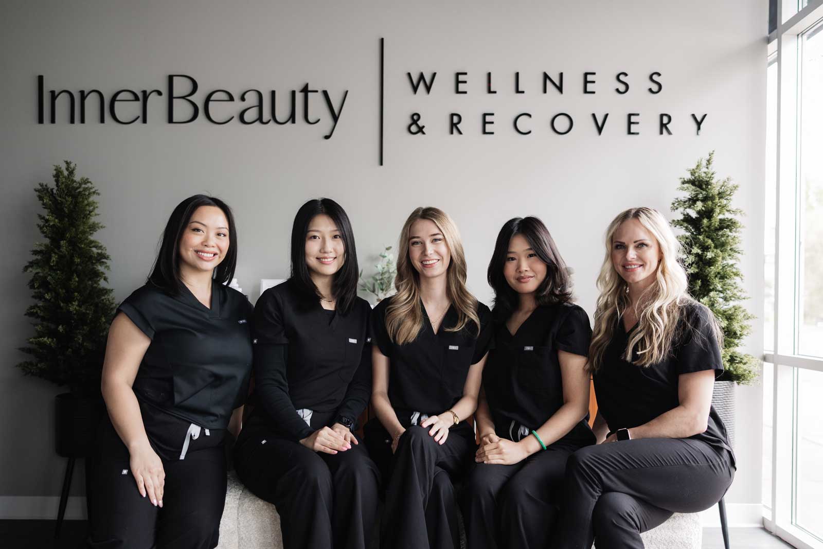 Five wellness staff in black scrubs at clinic